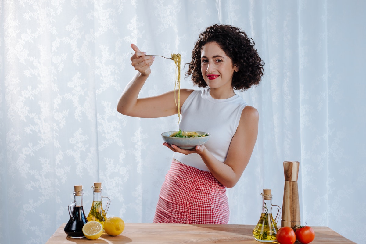 Fiatal nő egy tál ételt tart kezében. A mediterrán diéta alapjai és előnyei
